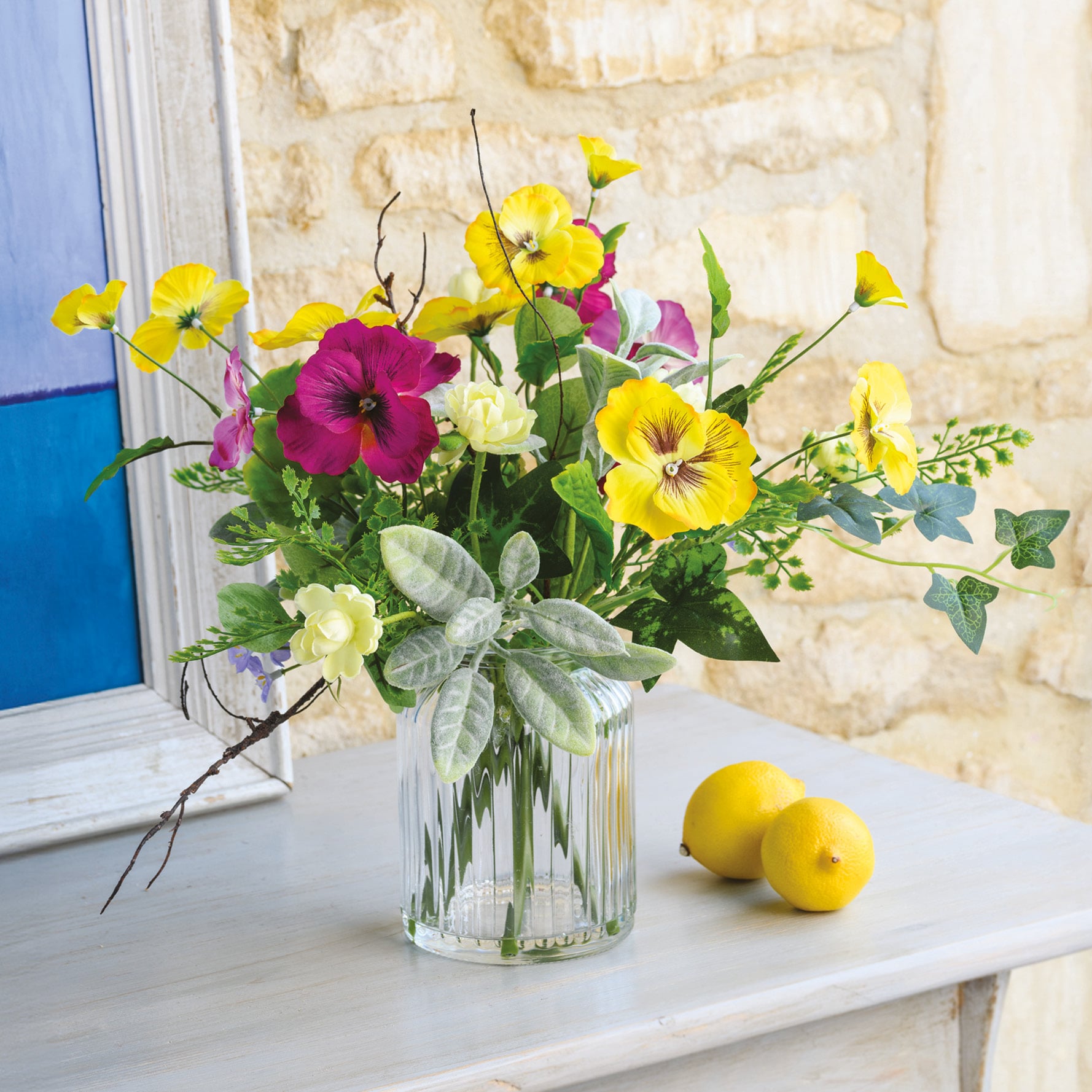 Faux pink and yellow Spring flowers in clear vase