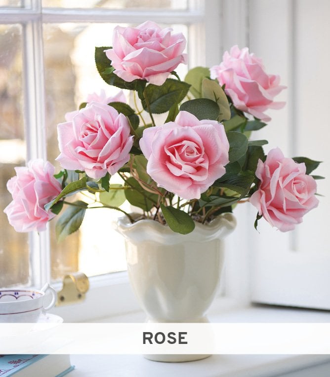 Pink faux roses in white ceramic vase