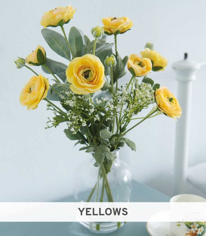 Yellow ranunculus stems in glass bottle vase